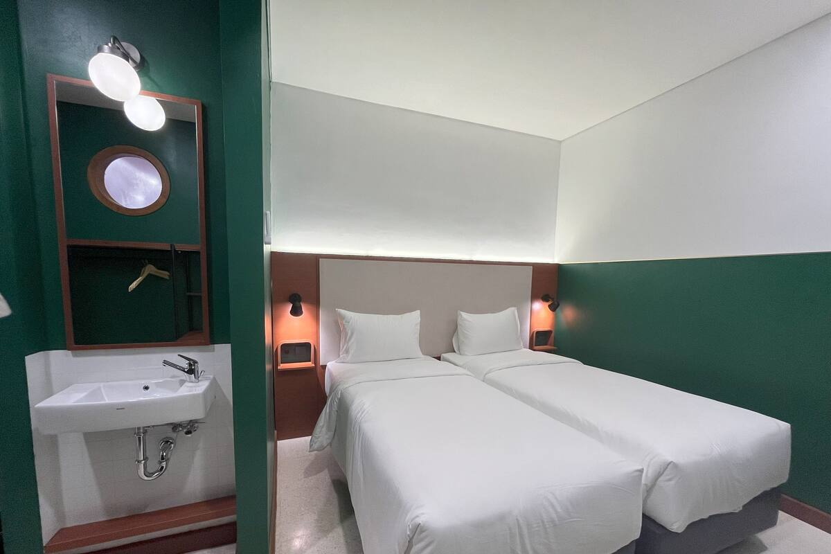 A hotel room with a double bed, a sink, and a mirror.