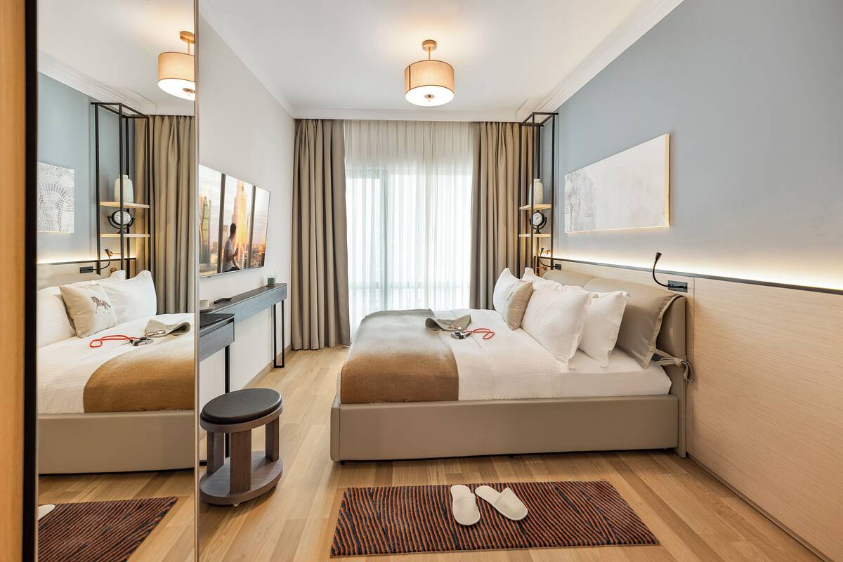 Ein modernes Hotelzimmer mit einem großen Bett, einem Schreibtisch und Blick auf die Stadt durch das Fenster.
