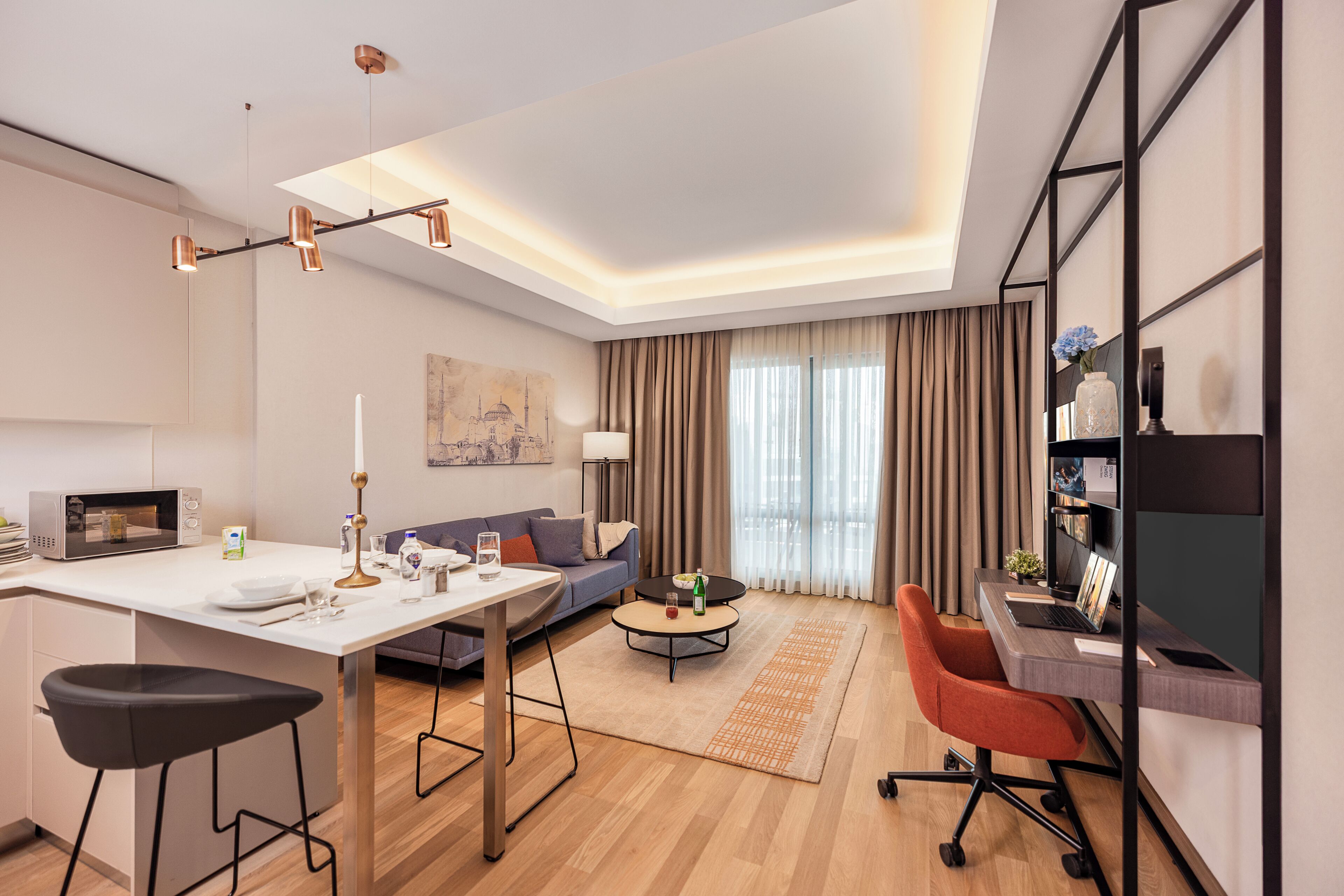 A modern living room with a dining area, a sofa, a coffee table, and a desk with a computer.