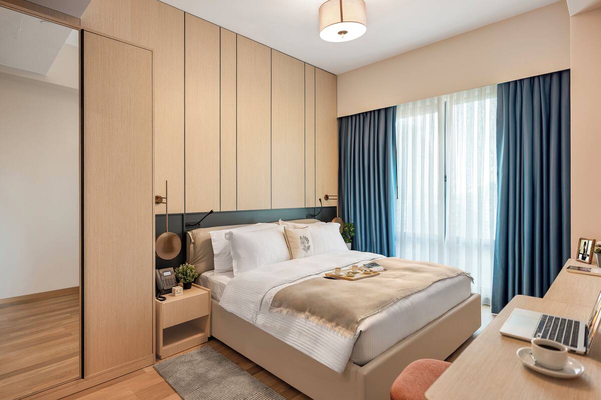 Ein modernes Hotelzimmer mit einem Bett, einem Nachttisch und einem Schreibtisch mit einem Laptop.