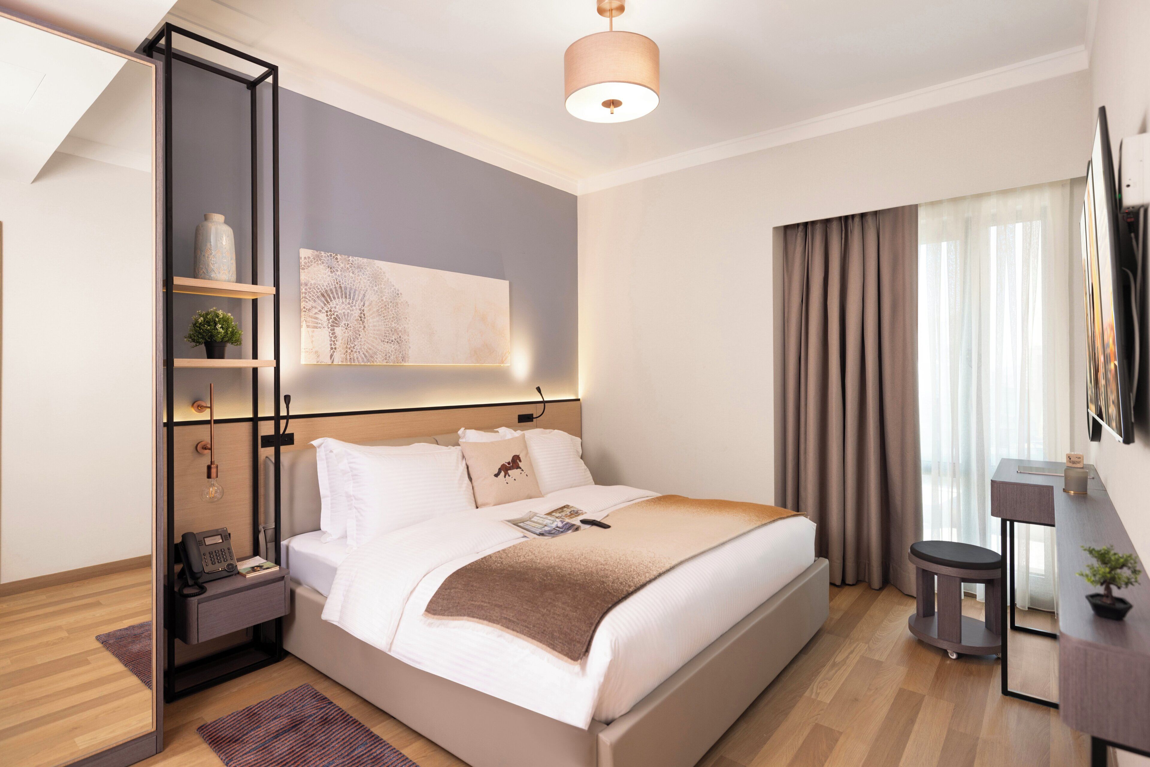 Una habitación de hotel moderna con una cama grande, mesitas de noche, un escritorio y un televisor.