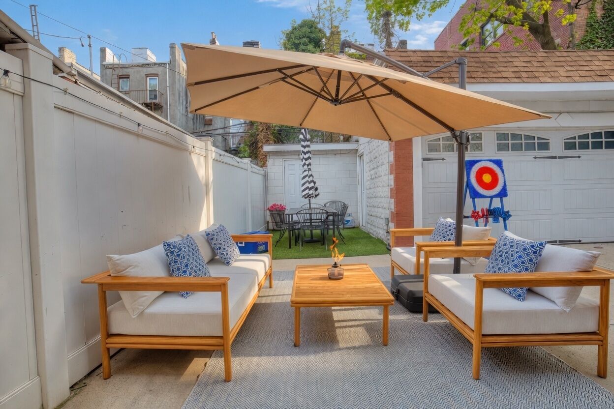 An outdoor patio with wooden furniture, a large umbrella, and a target in the background.