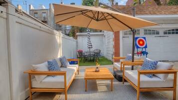 An outdoor patio with wooden furniture, a large umbrella, and a target in the background.