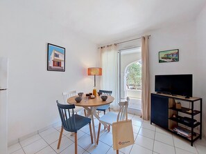 A dining area with a round table, chairs, a lamp, and a TV on a stand. - Parc de Pontaillac by Interhome (Vaux Sur Mer)