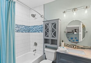 A bathroom with a bathtub, toilet, vanity with a mirror, and a shower with a curtain. - Charming house in delightful Destin with pool, AC, WiFi, private beach access (Destin)