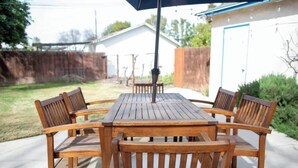 A wooden patio table with six chairs and a large umbrella.