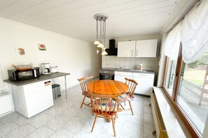 Cocina compacta con comedor, muebles blancos, microondas y estufa.