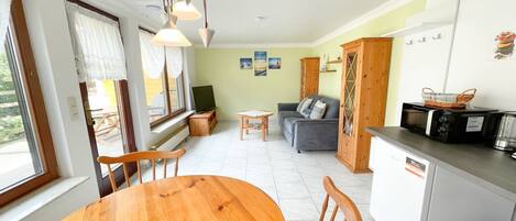 Un espacio habitable compacto con comedor, kitchenette y zona de estar.