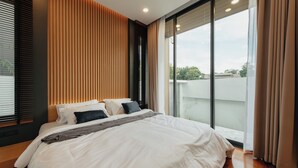 A modern bedroom with a large bed, wooden panel wall, and a view of the city through large windows. - TUL VIlla Chiangmai (Chiang Mai)