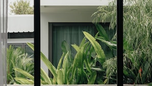 A modern building with a white facade, large windows, and a balcony with lush green plants. - TUL VIlla Chiangmai (Chiang Mai)
