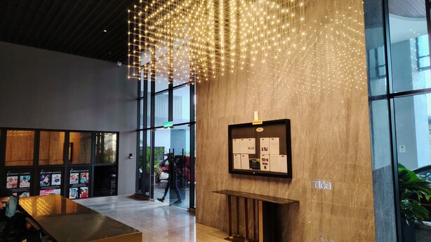 A modern lobby with a reception desk, a bulletin board with informational posters, and a large glass window. - Trion KL Residence by Sleepy Owl Suites (Kuala Lumpur)