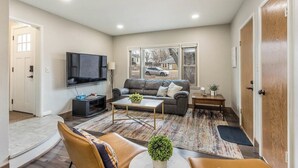 A living room with a sofa, coffee table, TV, and a view of the outside. - Beautiful Get-a-way in the Heart of Sioux Falls (Sioux Falls)