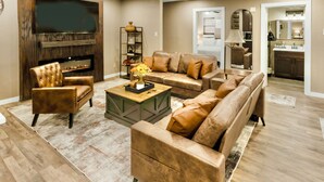A spacious living room with a large flat-screen TV, leather sofas, and a wooden coffee table. - A&M Cabin-Pool Table Deck BBQ-10mins Kyle Field (Bryan)