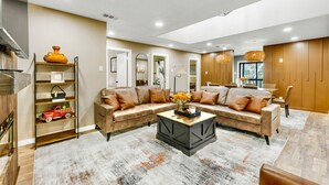 A modern living room with a sectional sofa, a coffee table, and a bookshelf. - A&M Cabin-Pool Table Deck BBQ-10mins Kyle Field (Bryan)