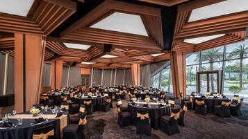 A conference room with multiple tables, black chairs with gold sashes, and a modern ceiling design.