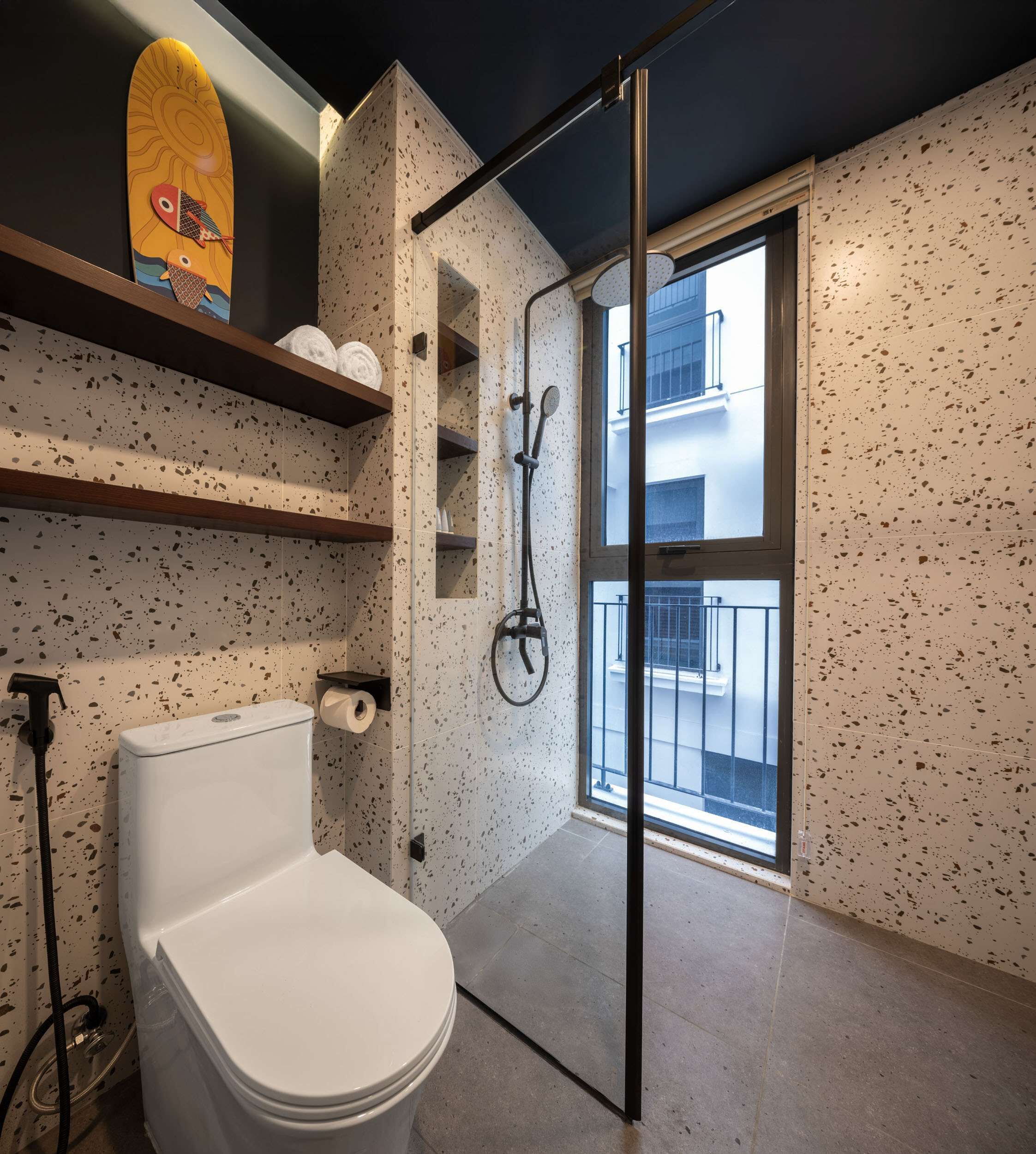 A modern bathroom with a shower, toilet, and a window overlooking a building.