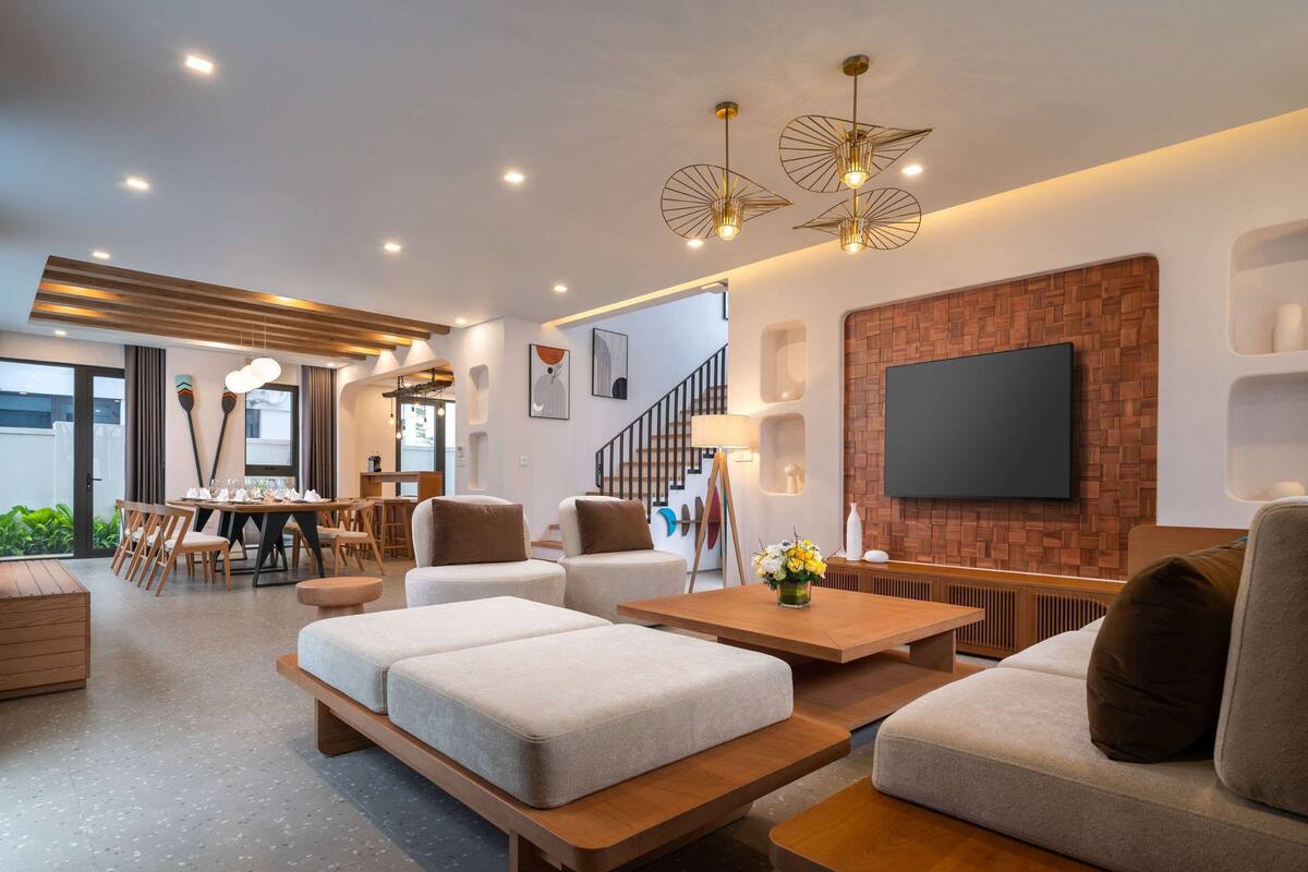 A modern living room with a wooden coffee table, sofas, and a dining area with chairs.