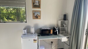 A compact kitchenette with a refrigerator, microwave, toaster, coffee maker, and a small trash bin. - Country Getaway - Studio room with Ensuite in seven-acre landscaped gardens. (Waitohi)