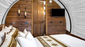 Una habitación acogedora con arco, una cama, un televisor en la pared y paneles de madera.