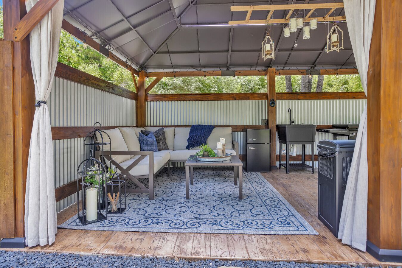 A covered outdoor seating area with a sofa, table, and grill.