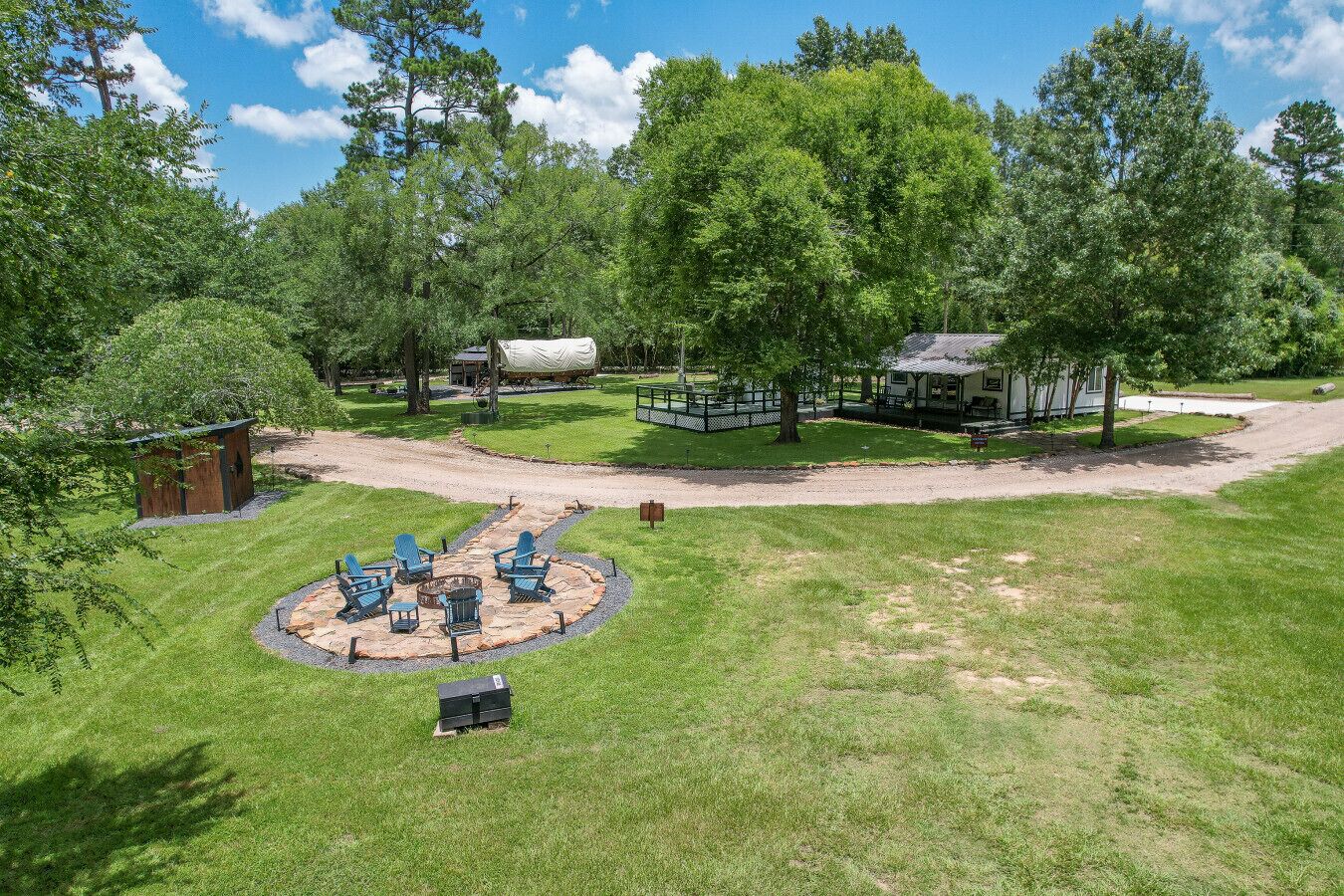 A well-maintained outdoor area with a circular seating arrangement, a covered picnic table, and a small wooden structure.