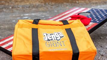 Un sac de jeu Jenga géant posé sur une table, avec un drapeau américain à proximité.