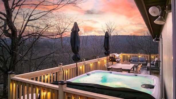 Une terrasse en bois avec un jacuzzi, des sièges d’extérieur et des guirlandes lumineuses.