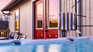 Un bain à remous avec une terrasse en bois, une porte rouge et un porte-serviettes.