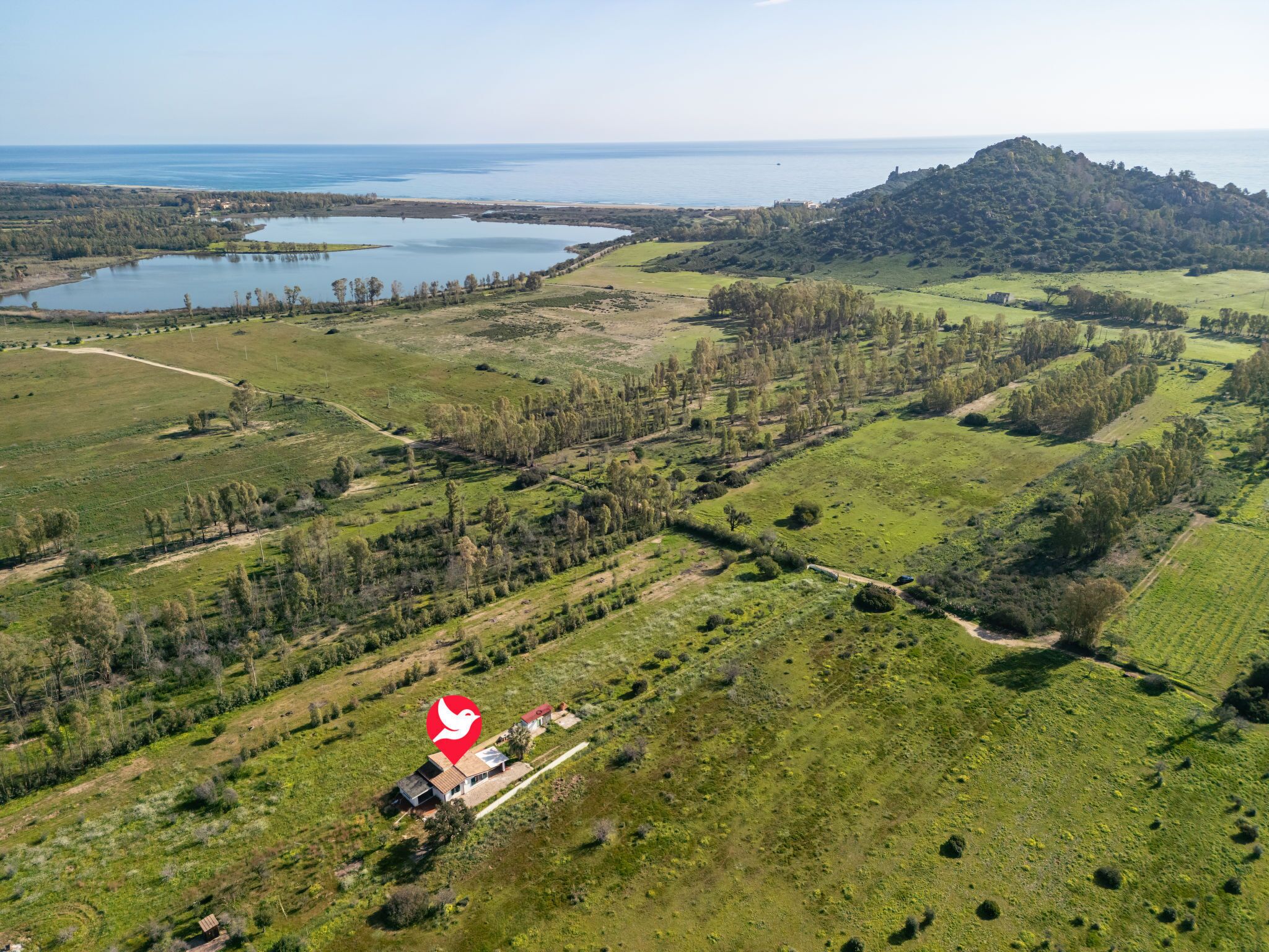Luchtbeeld van een landelijk gebied met velden, een meer en een heuvel.