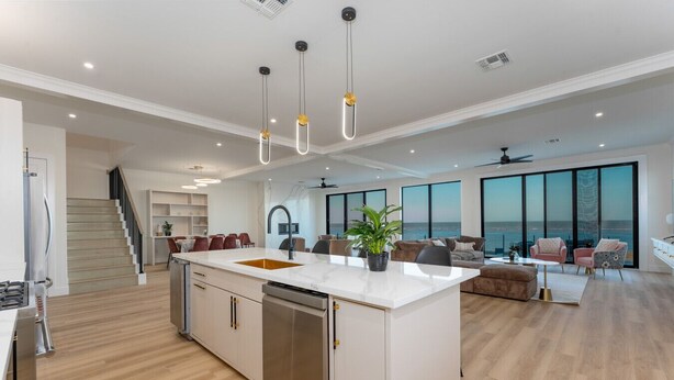 A spacious living area with a large island, modern kitchen, and a view of the ocean. - NEW Luxury 4,000 SF Waterfront Home, With Pool, Sleeps 20 (Port Isabel)