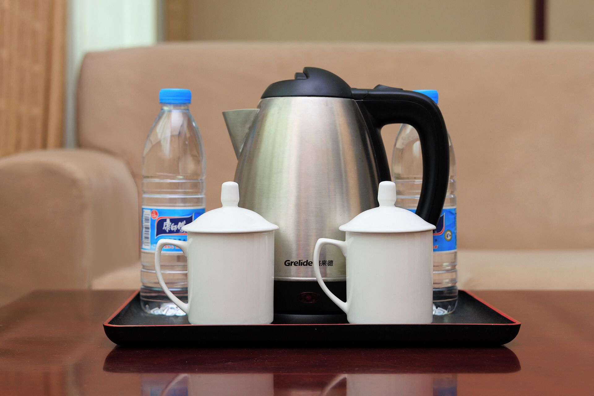 A tray with a kettle, two teapots, and two water bottles on a table.