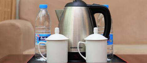 A tray with a kettle, two teapots, and two water bottles on a table.