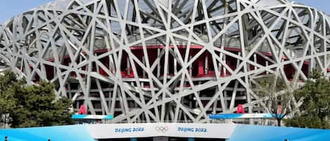 A large, modern stadium with a distinctive geometric design, featuring multiple levels and a prominent central structure.