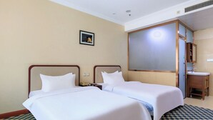 Ein Hotelzimmer mit zwei Betten, einem Badezimmer und einem kleinen Schreibtisch.