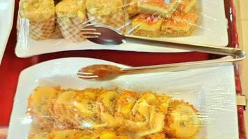 Two trays of food items wrapped in plastic, one containing pastries and the other containing breaded and fried items.