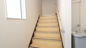 Eine Treppe mit beigen Stufen und einem Geländer, die zu einem Raum mit einer weißen Tür und einem Fenster führt.