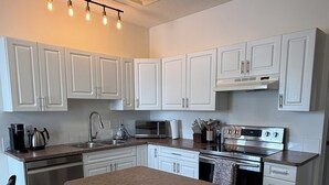 A modern kitchen with white cabinets, a central island, stainless steel appliances, and a pendant light fixture. - Family-friendly remodelled historical church to private suits!
10 min to Costco! (Redcliff)