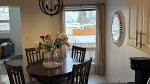 A dining area with a round table, chairs, a vase with flowers, a chandelier, and a view of a snowy landscape through a sliding door. - Family-friendly remodelled historical church to private suits!
10 min to Costco! (Redcliff)