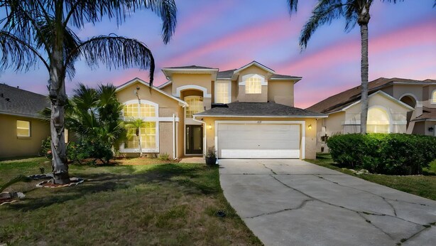 A two-story house with a garage, surrounded by a well-maintained lawn and palm trees. - Home in the historic Disney World
Peaceful, Cozy six bedrooms with nine beds (Kissimmee)