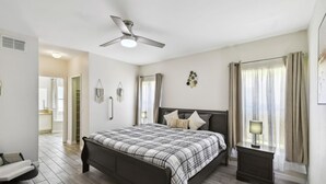 A bedroom with a bed, bedside tables, a ceiling fan, and a window with curtains. - Home in the historic Disney World
Peaceful, Cozy six bedrooms with nine beds (Kissimmee)