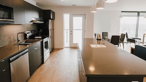 A modern kitchen with stainless steel appliances, a large island, and pendant lighting. - Chic Retreat w/Balcony in the Heart of Winnipeg (Winnipeg)
