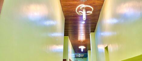 A hallway with a wooden ceiling and a modern light fixture.