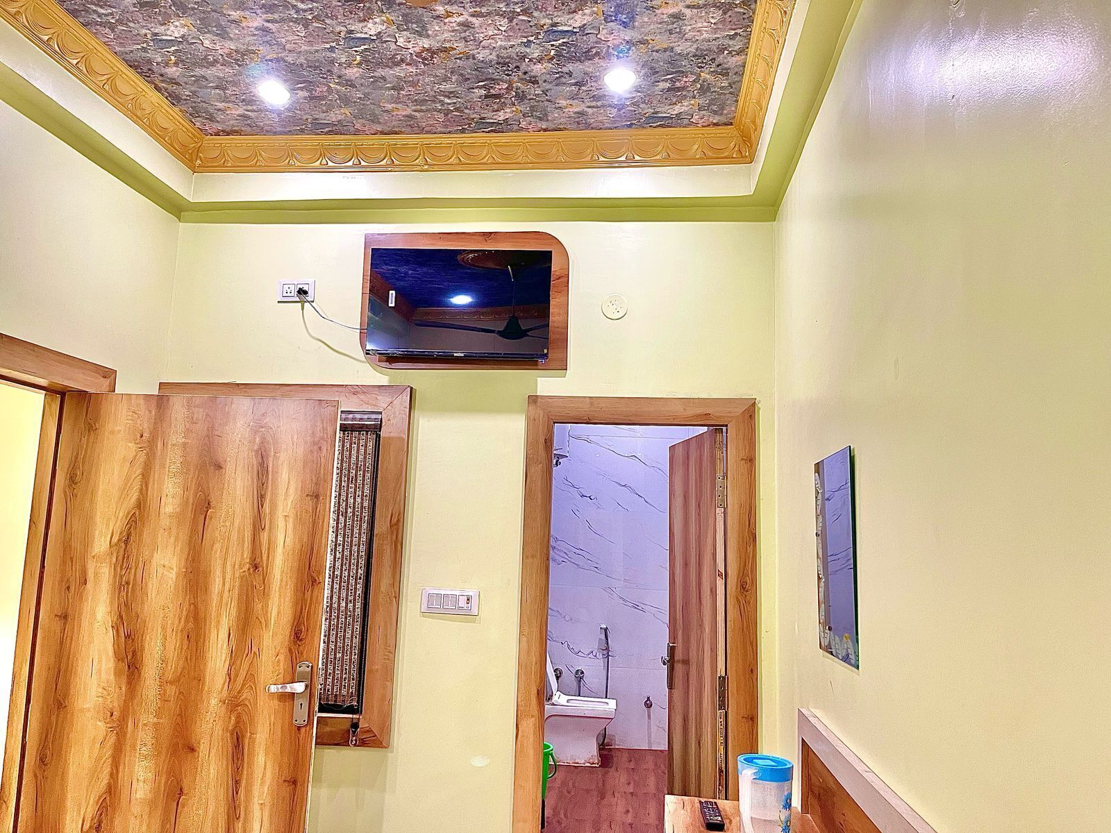Un baño con puerta de madera, un lavamanos integrado, un espejo y un techo con diseño decorativo.