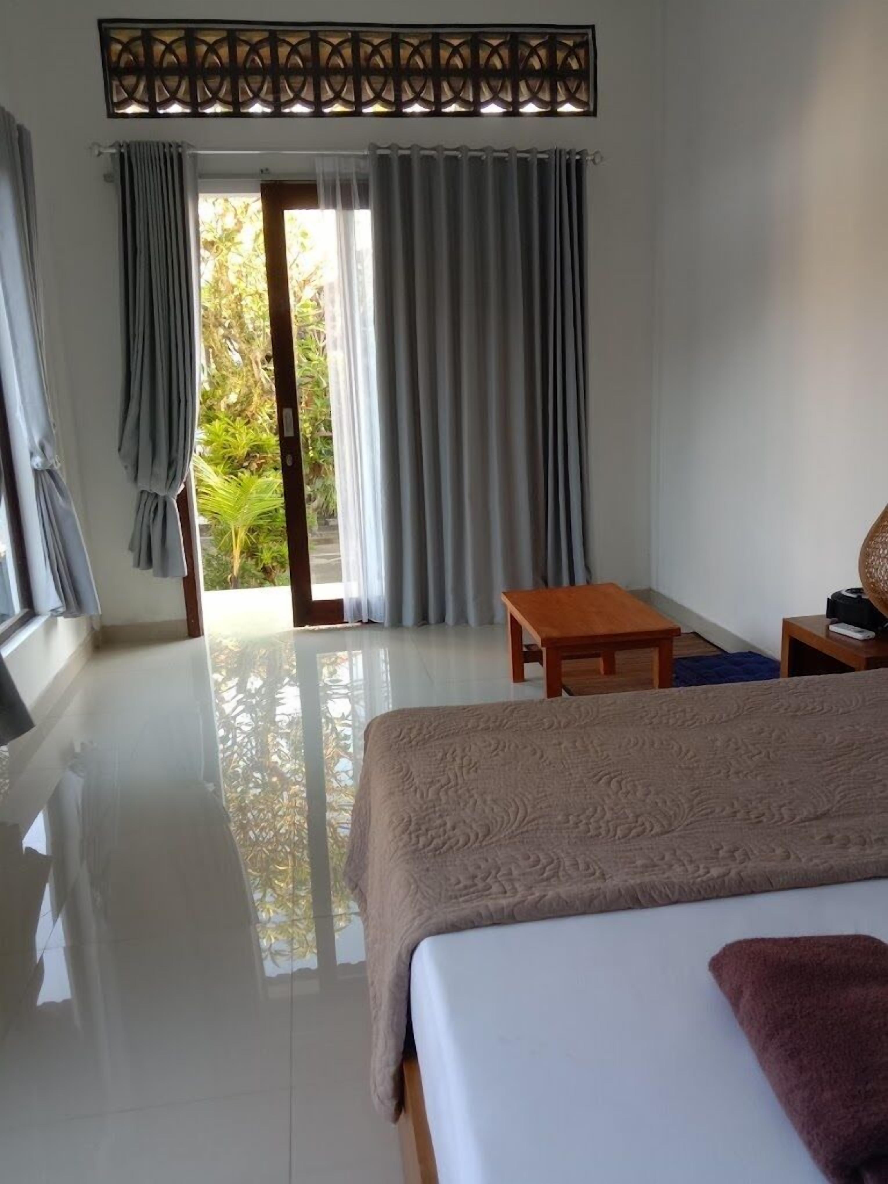 Une chambre d’hôtel avec un lit, une table en bois, un bureau et une vue sur l’extérieur grâce à une porte vitrée.