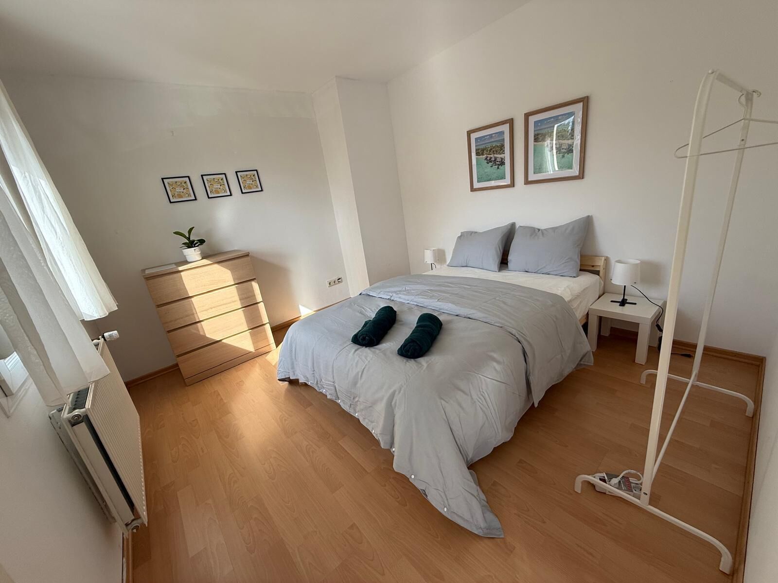 A bedroom with a bed, bedside tables, a dresser, and a radiator.
