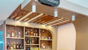 A bar and restaurant with a wooden counter, shelves of bottles, and a sign above. - Hotel badrinath (Kathmandu)
