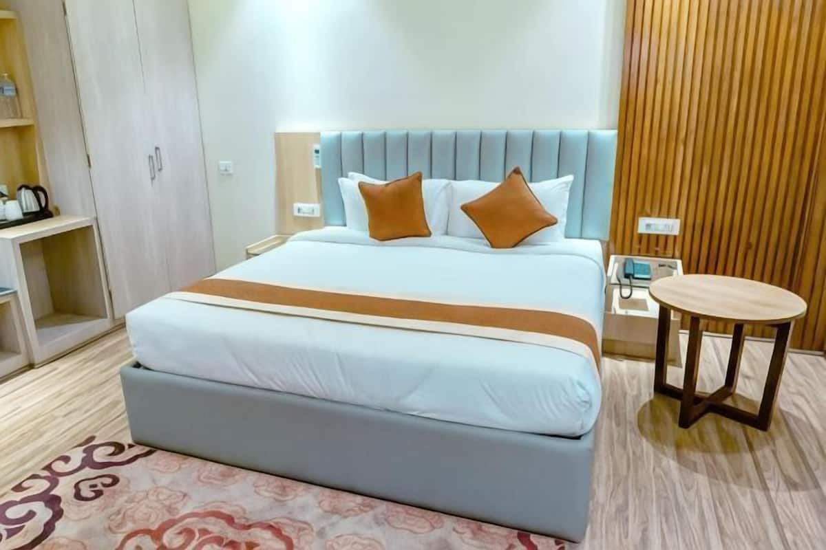 A hotel room with a bed, bedside table, and a small round table.