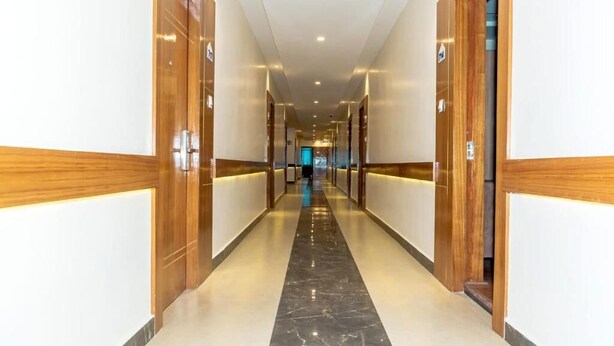 A hotel corridor with wooden doors, a marble floor, and a central light strip. - Hotel badrinath (Kathmandu)