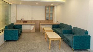 A modern, well-lit room with teal sofas, a wooden table, and a counter. - Hotel badrinath (Kathmandu)