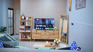 En moderne stue med et fladskærms-tv, en reol, en sofa og et spejl.